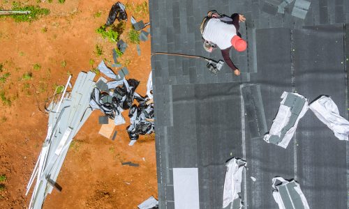 Air nail gun is used by roofing contractor to install new asphalt bitumen shingles on roof of house